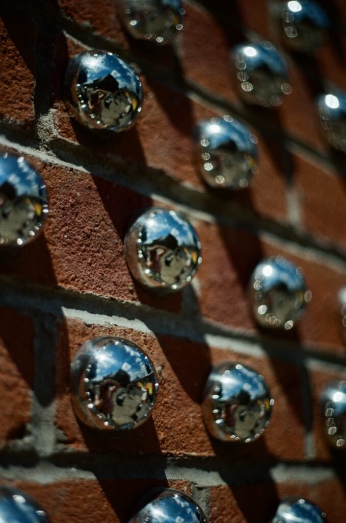 Silver half spheres attached to a brick wall in a pattern