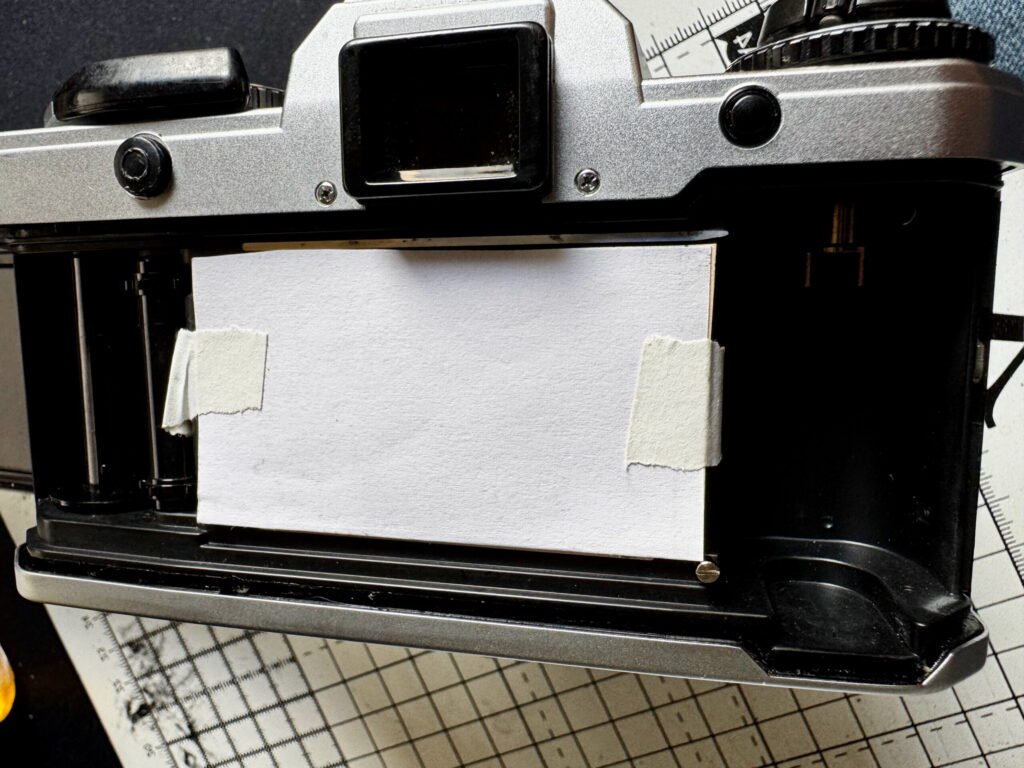 Yashica FX-D film chamber open, with protective card covering the shutter blades.